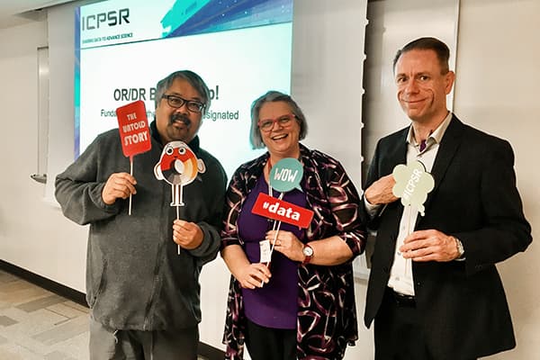 Three ICSPR representatives holding signs related to data